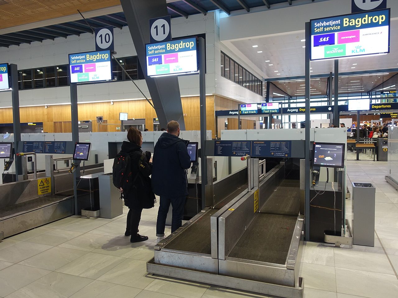 Passengers using self-service bag drop machines to check in luggage